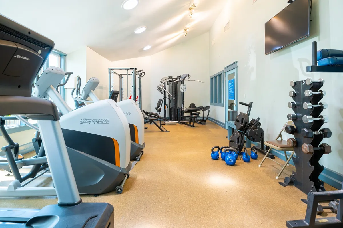 A motivational fitness center filled with treadmills, weight machines, kettlebells, and dumbbells. The space is designed for both solo workouts and group fitness activities, featuring modern equipment and an energetic vibe.