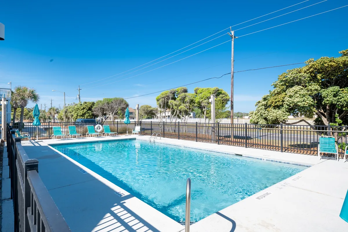 An inviting exterior shot featuring a swimming pool surrounded by lounge chairs and lush greenery. The tranquil atmosphere offers a sense of relaxation in nature's embrace, with glimpses of the surrounding landscape.