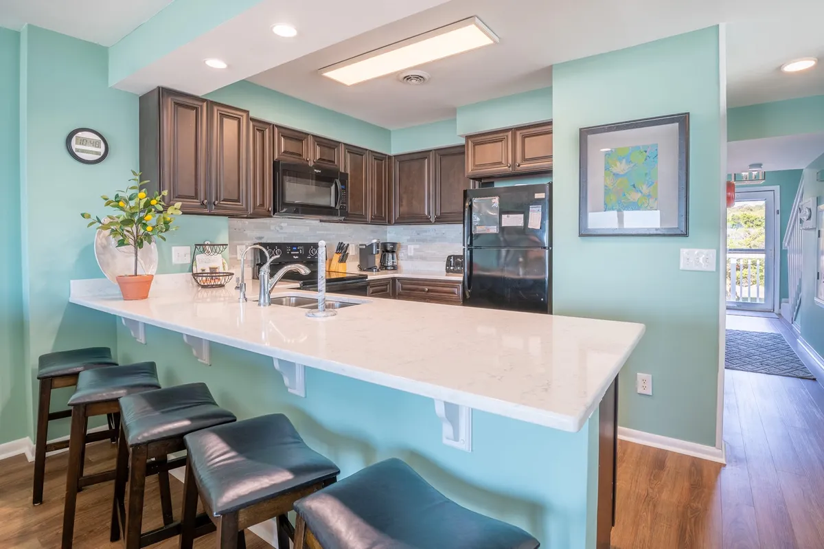 A modern kitchen with a central island featuring bar stools, sleek cabinetry, and a well-equipped countertop with a sink. The space feels bright and welcoming, encouraging both cooking and casual dining.